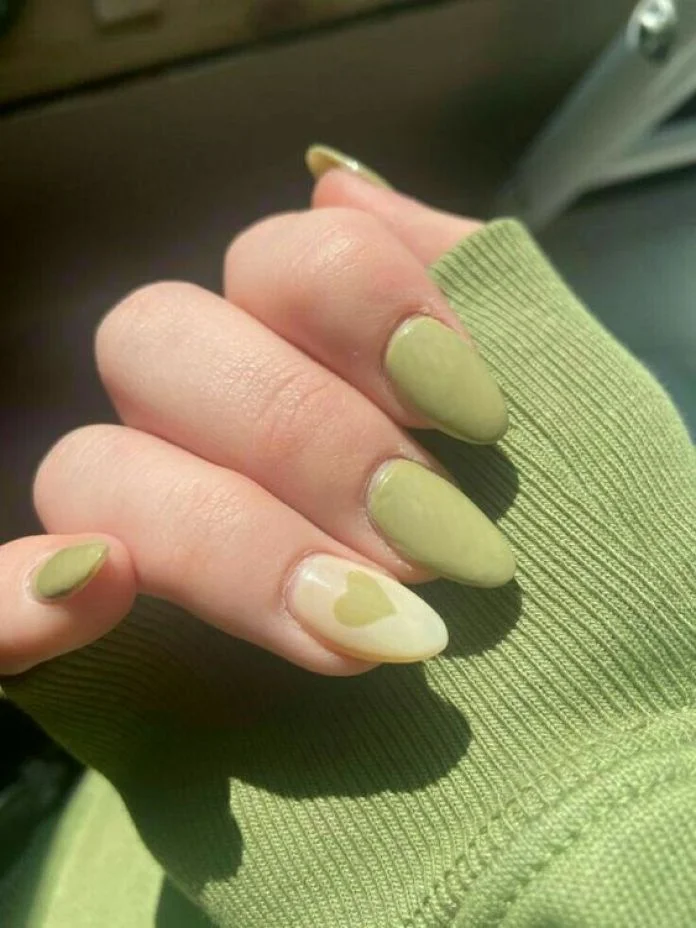 Pistachio green manicure, hand resting on a green knit sleeve